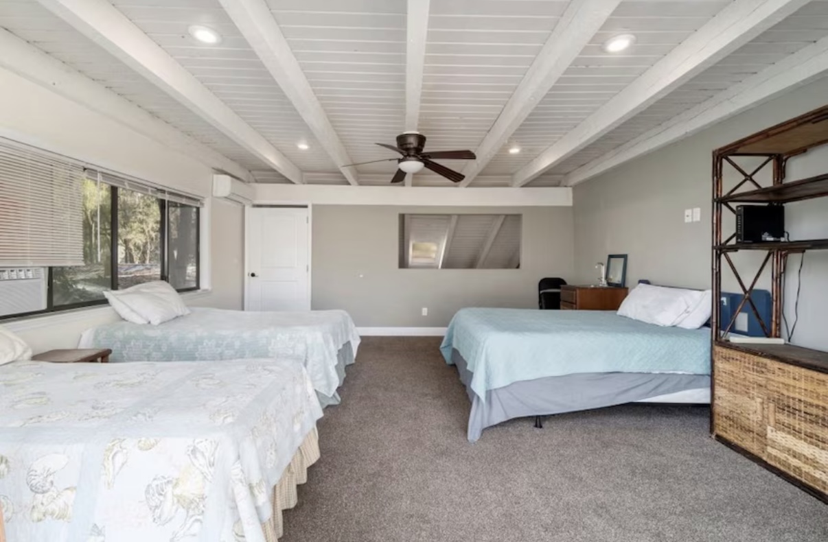 Large dormitory room with multiple beds and exposed beams
