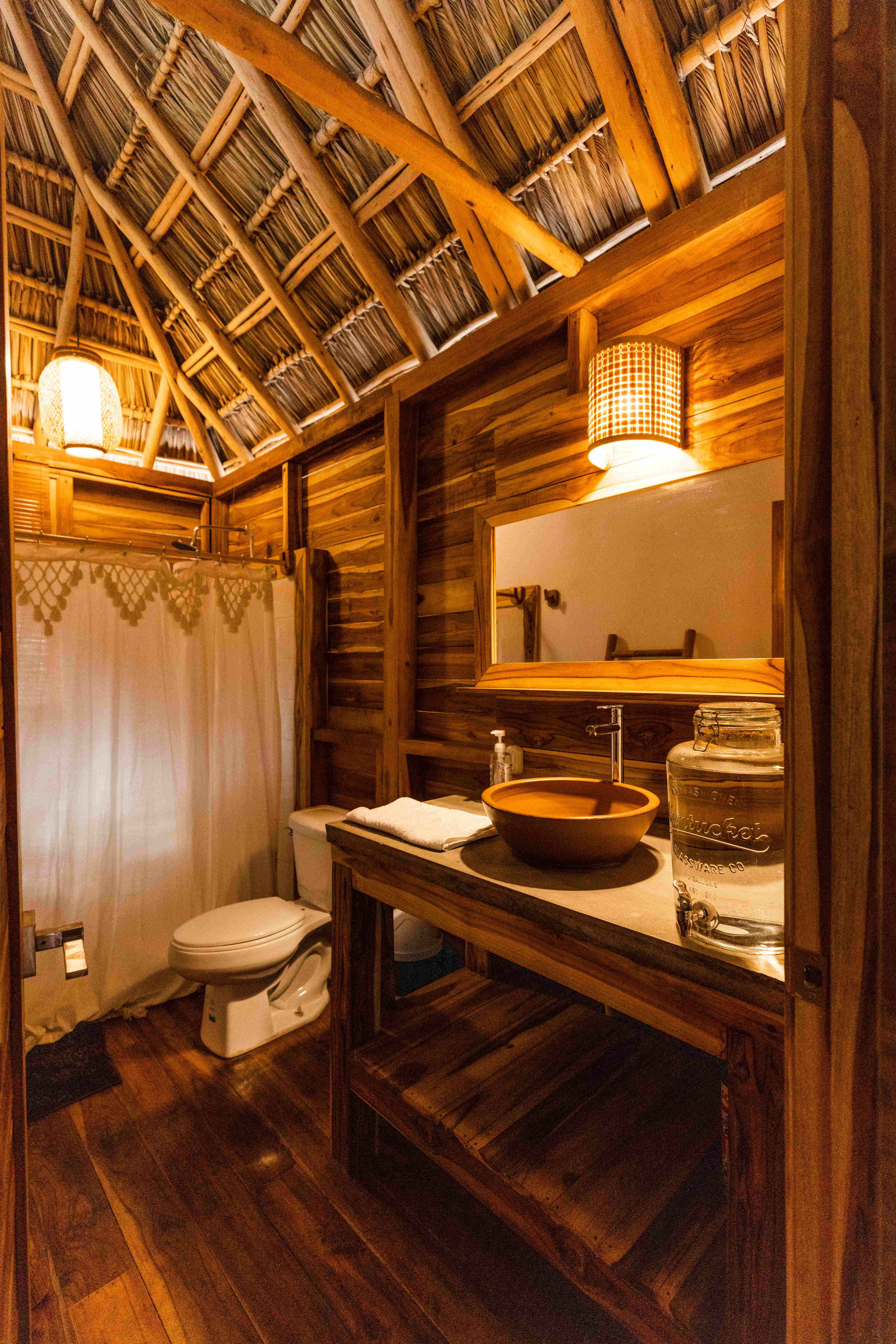 Rustic eco-luxury bathroom with thatched roof and wooden elements