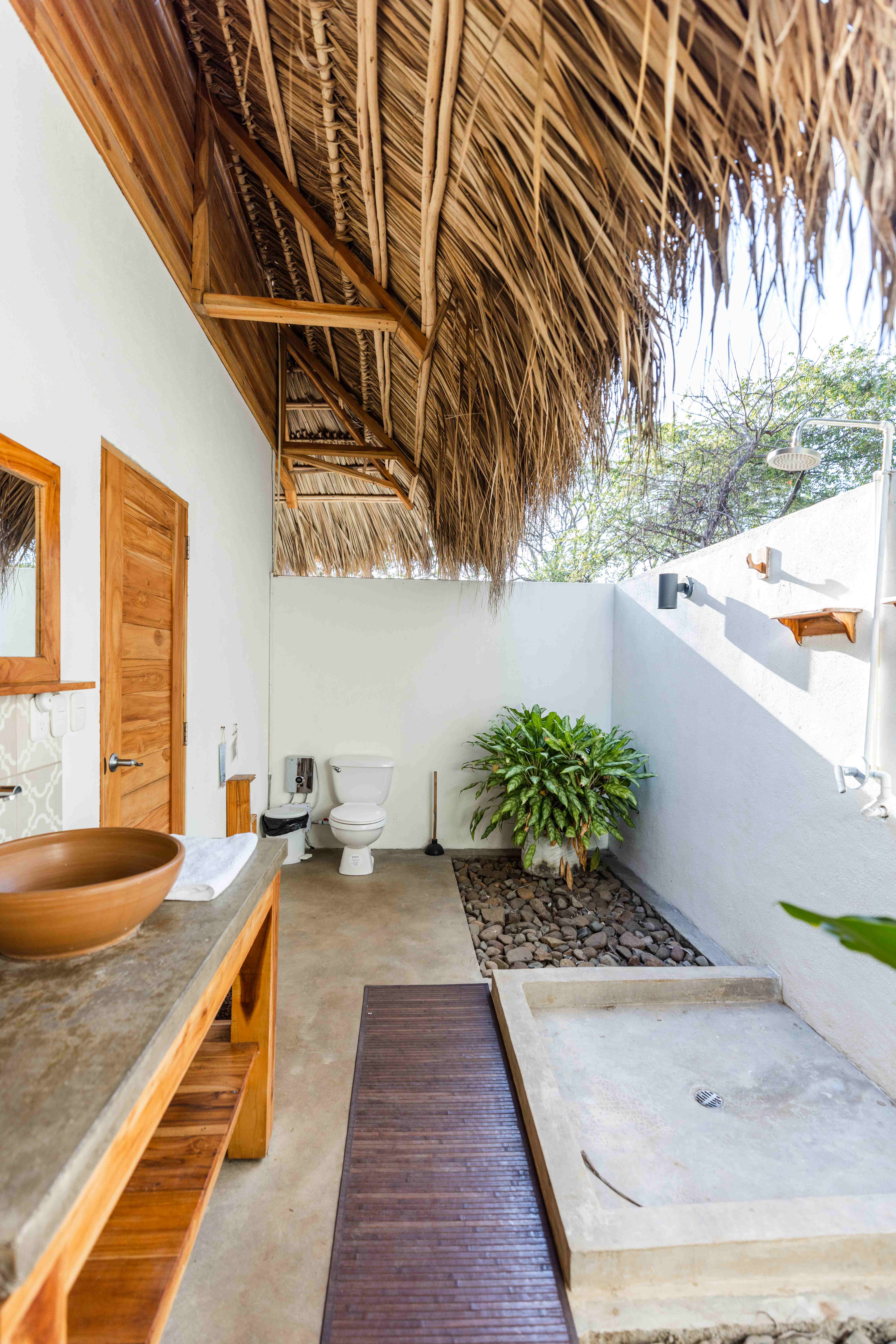 Open-air bathroom with tropical plants and natural materials