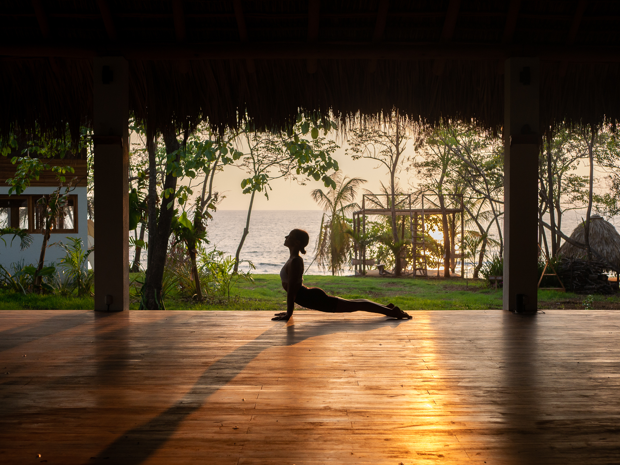 Silhouette of yoga practice at sunset on wooden deck