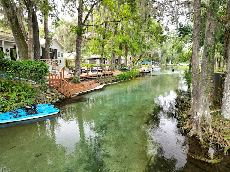 Wide view of crystal clear spring water with house and decks